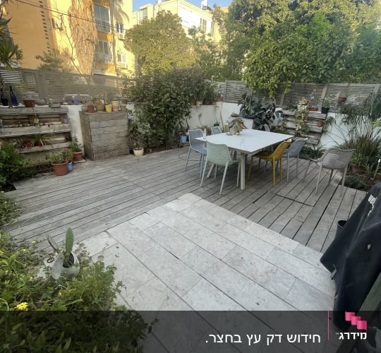 עציצים על מדפים מעץ בגינה, שולחן וכיסאות צבעוניים